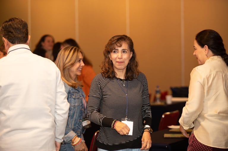 Group of people having a casual conversation at an indoor event with warm orange wall background