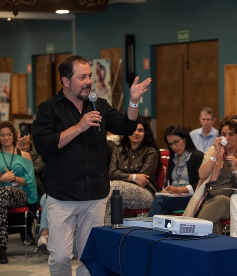 Man speaking passionately at a microphone in front of an audience seated in a conference or event room